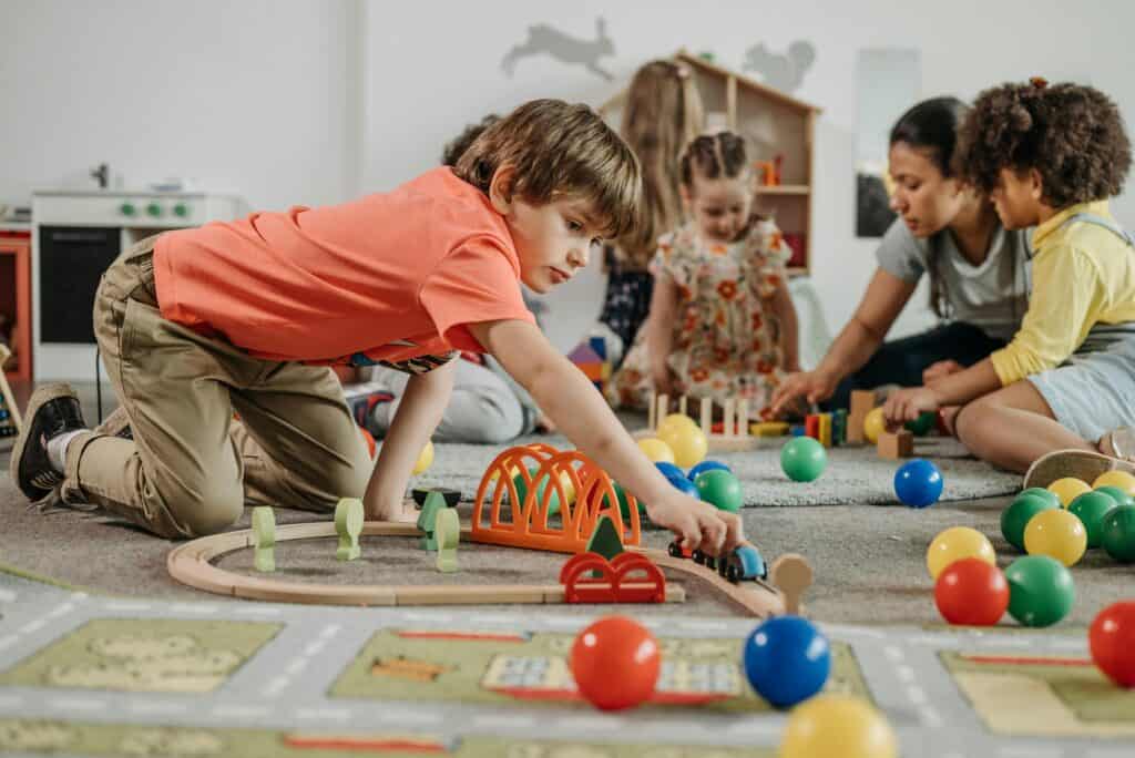 Children playing with toys in a nursery while an early years practitioner supervises