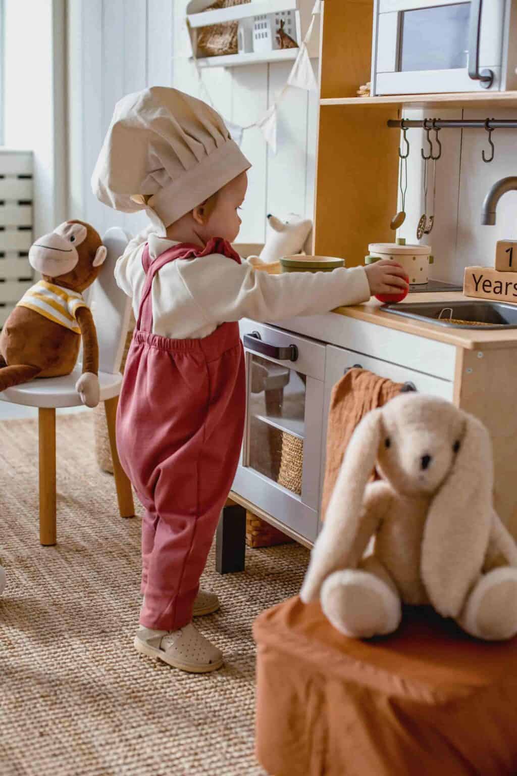 Child exploring role play kitchen in a calm child-led nursery environment with natural materials