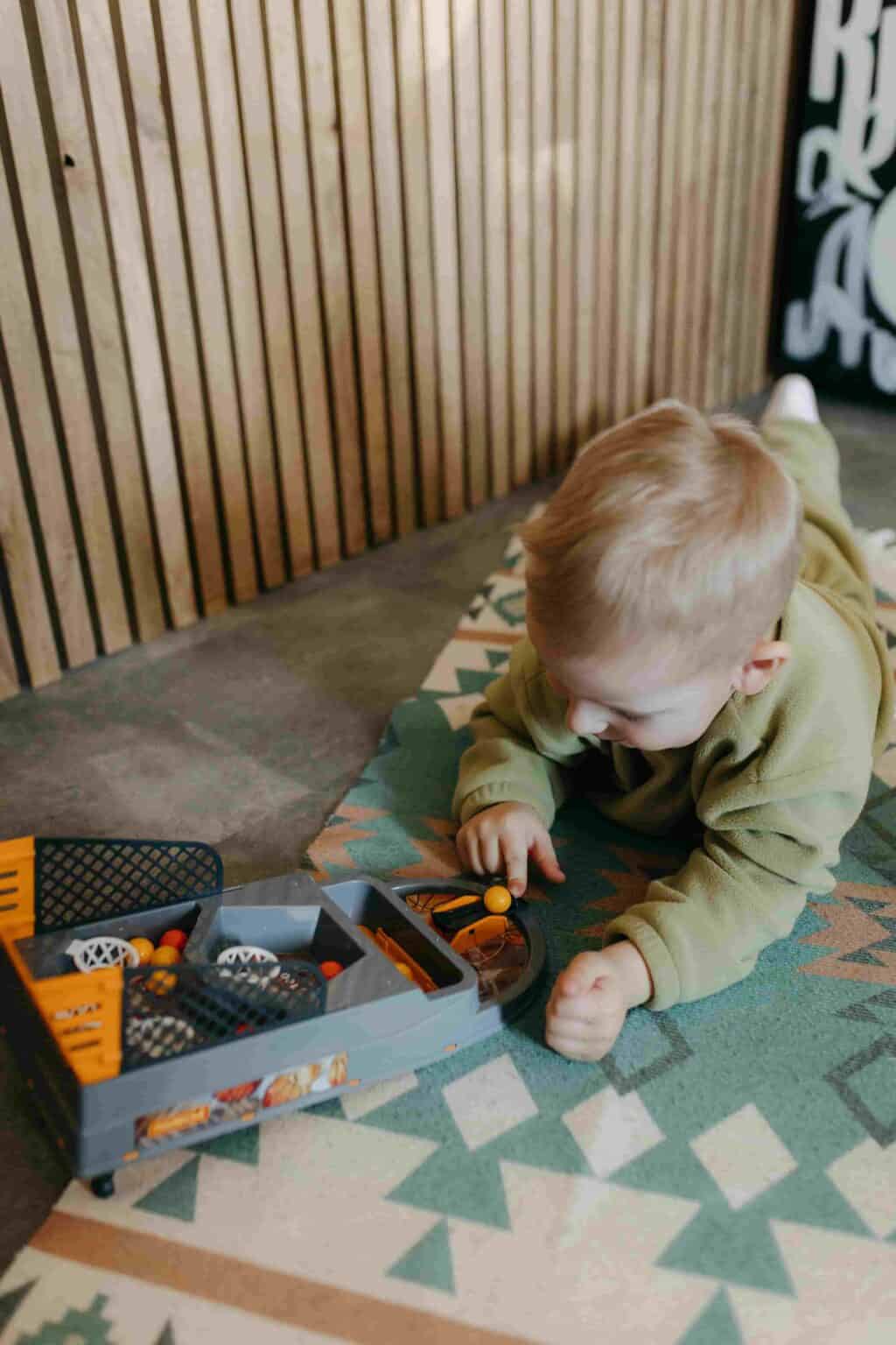 Child playing independently with toys on a mat at nursery in Leyton