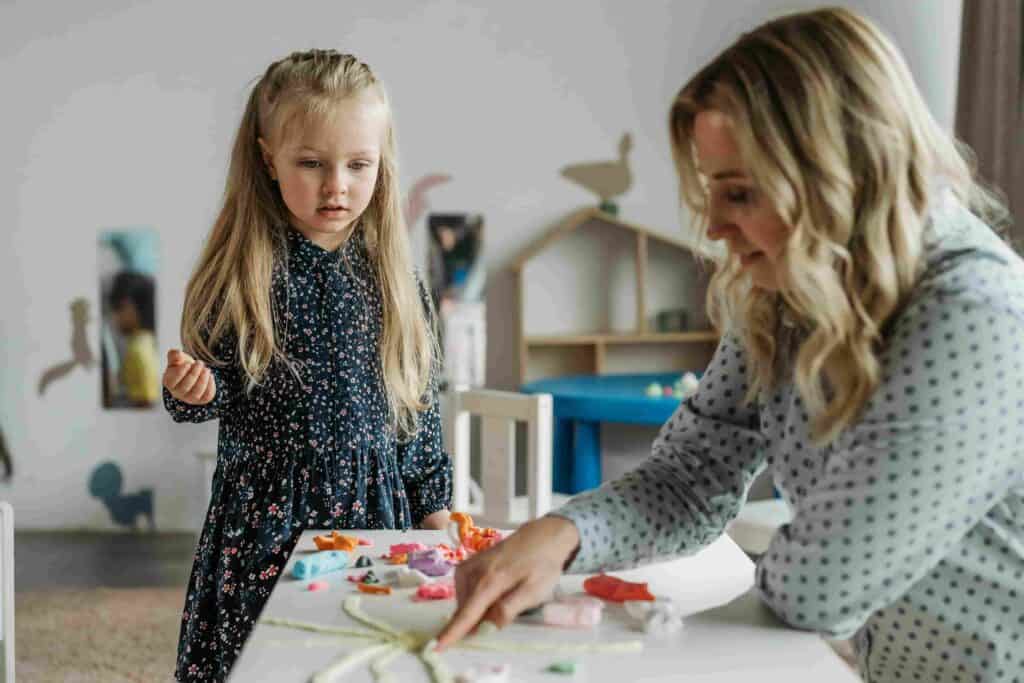 Nursery key worker supporting child through play activity