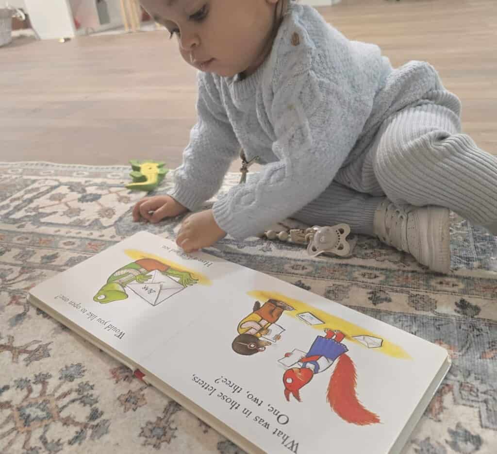 18 month old settled at nursery reading book in calm environment