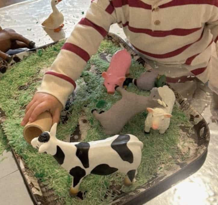 Young child exploring sensory farm animal play at nursery in Leyton