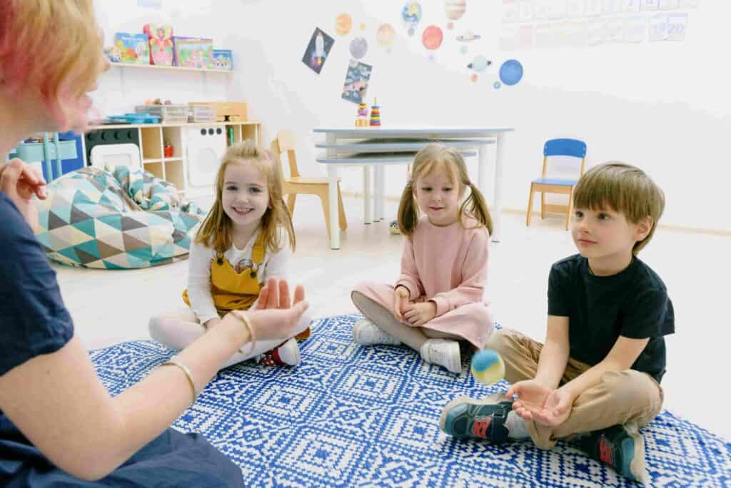 Children taking part in preschool group activity with early years practitioner