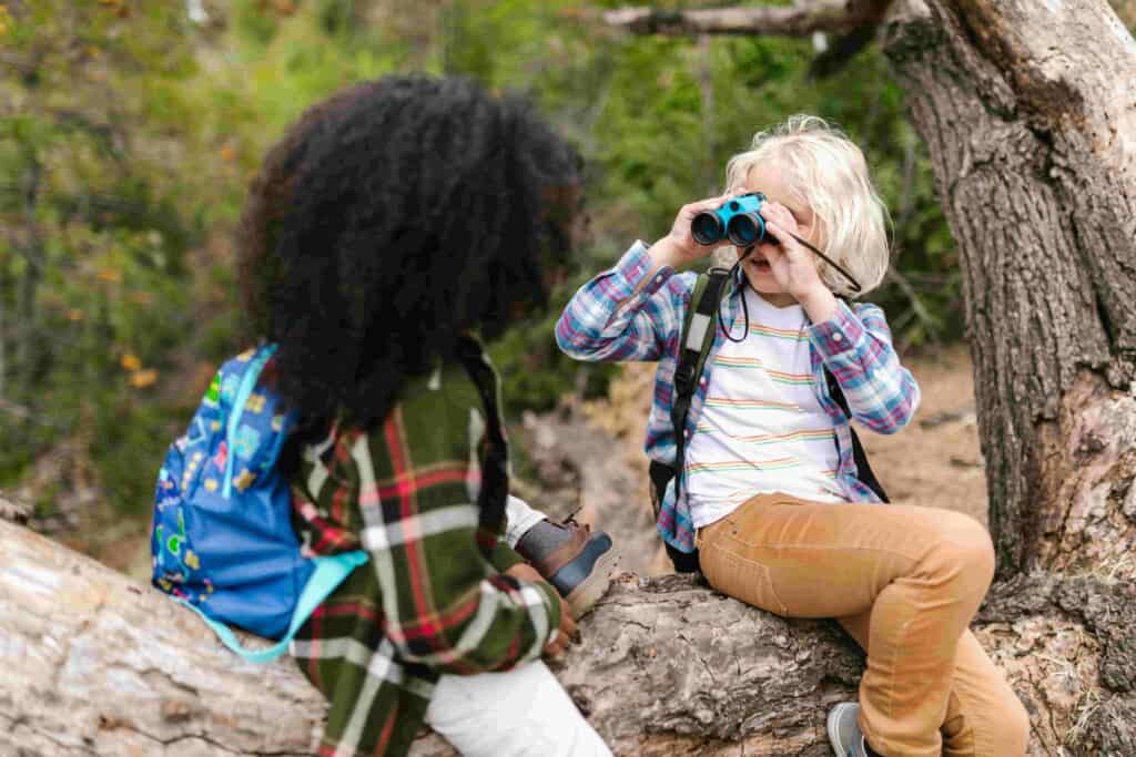 Young Children exploring nature together with binoculars