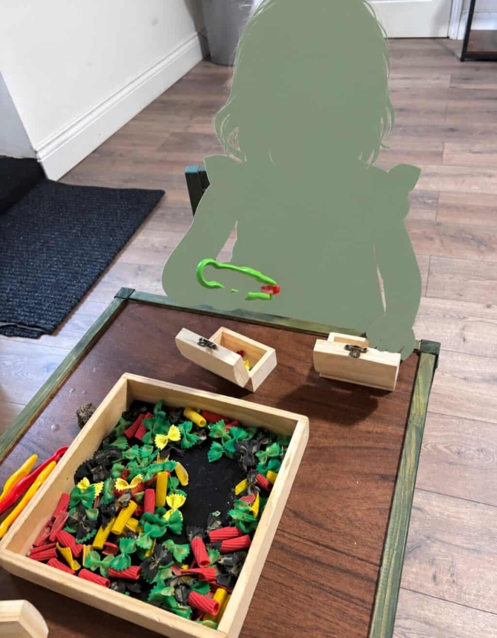 Child exploring open-ended materials with wooden resources and fine motor tools at The Nook Nursery