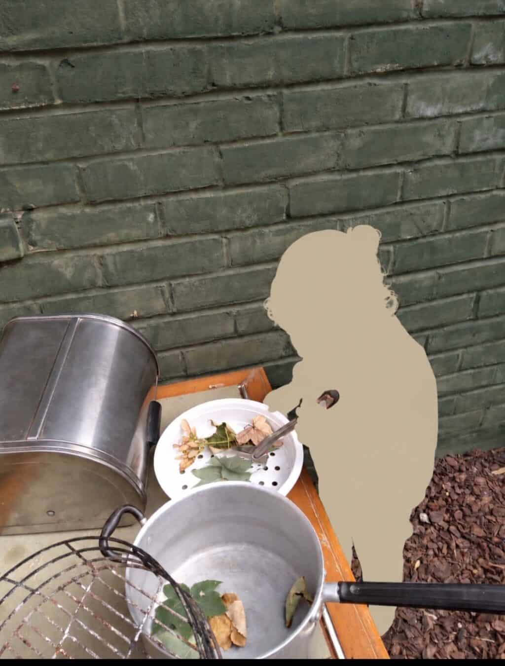 Child exploring natural materials with outdoor cooking utensils at The Nook Nursery